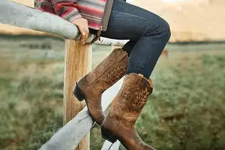Brown leather cowboy boots with intricate stitched designs.
