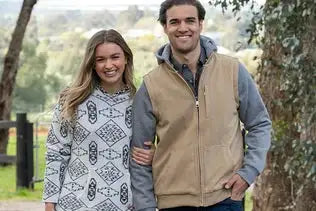 The man is wearing a tan and gray zip-up vest with a hood.