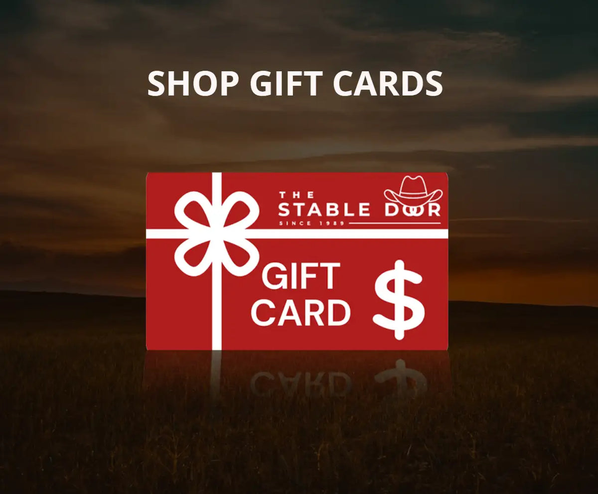 Red rectangular gift card featuring a white bow, ’the stable dwr’ logo with a cowboy hat icon, and the words ’gift card’ alongside a dollar sign.