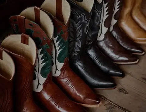 A row of classic cowboy boots in rich brown, black, and tan leather with intricate stitched designs and decorative patterns on the shafts.