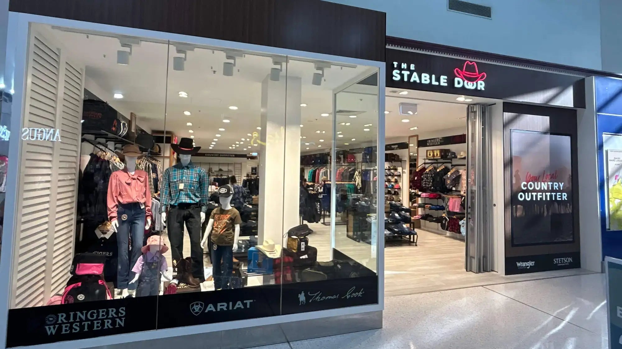 The stable door store entrance features a black sign with white lettering and a red cowboy hat logo above the doorway.