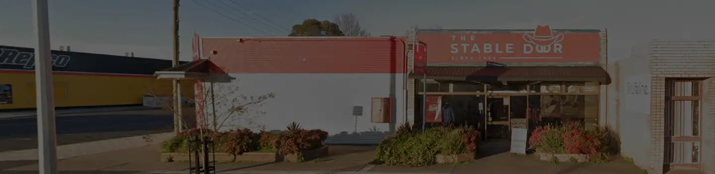 The stable dour sign features bold white lettering on a red background with a cowboy hat emblem above the text.