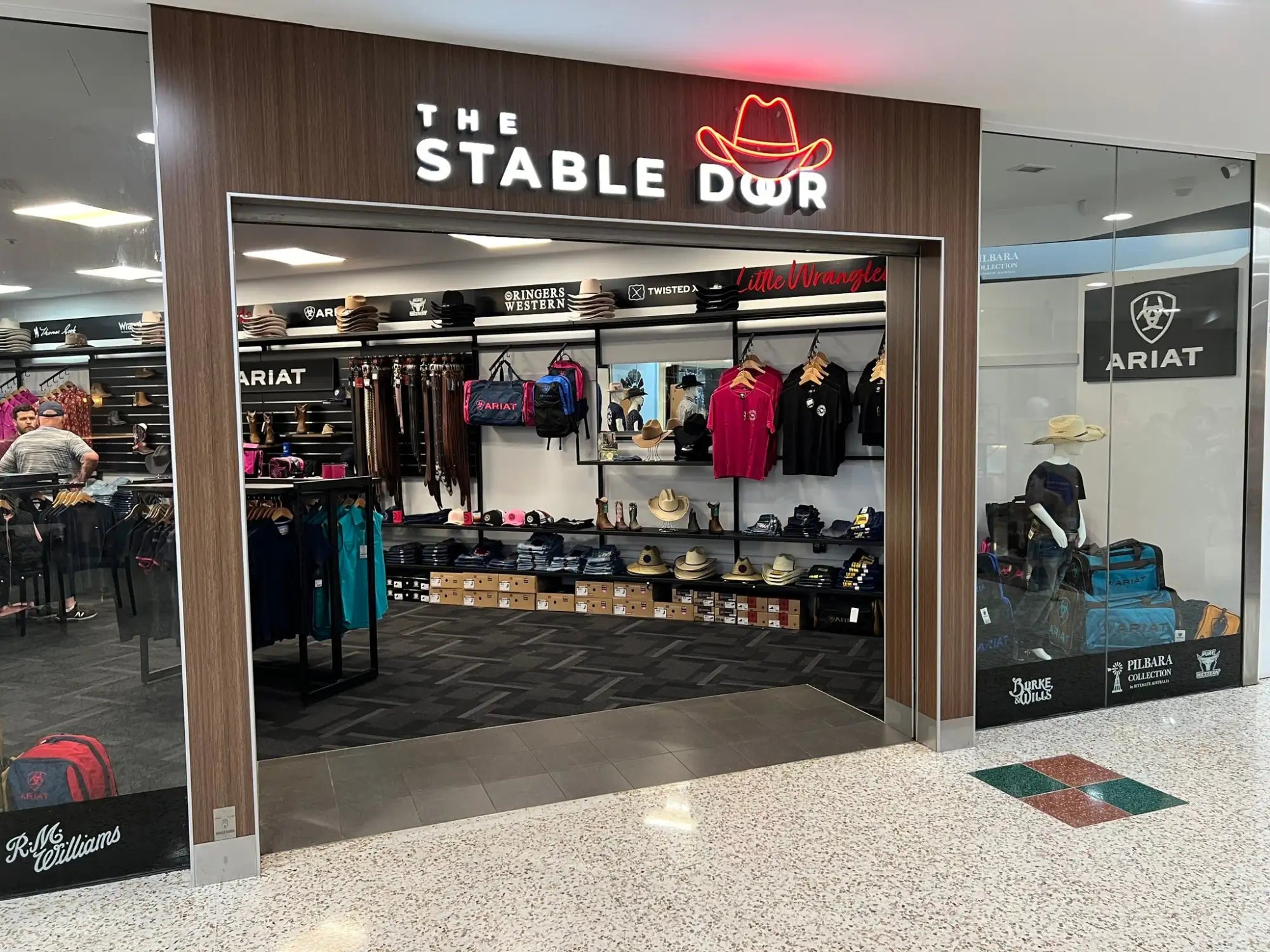 The stable dwr store entrance features a prominent neon sign with the brand name and logo above glass doors.